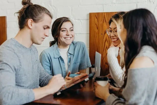 Four people sitting around a desk, smiling.